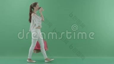 带着袋子的年轻女子在绿色屏幕上随意<strong>走动</strong>，喝茶