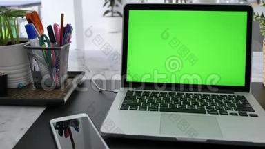 在客厅的办公桌上展示绿色彩色钥匙屏幕的笔记本电脑。 在背景舒适的客厅里。 多利鞋