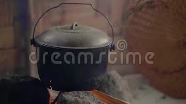 在篝火上用风扇吹火做饭。 准备传统火锅烧柴火的晚餐