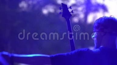 摇滚音乐家在音乐会上从舞台上演奏电吉他。 在聚光灯下双手特写