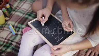 一个小女孩学会用粉笔<strong>在黑板上写字</strong>。妈妈教女儿<strong>写字</strong>母、字母表