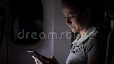 夜间靠窗<strong>坐飞机</strong>的智能手机女人