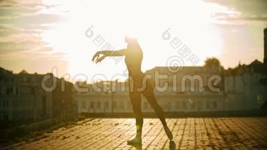 年轻优雅的女芭蕾舞演员在屋顶上训练她的舞蹈-明亮的日落