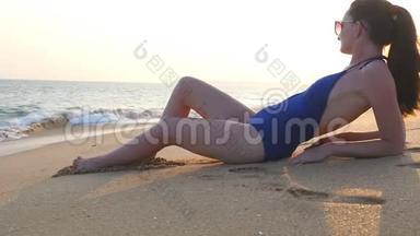 穿着泳衣躺在海边和日光浴的年轻女孩。 美丽的白种人女人在海边放松