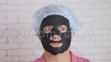 男人用一个恢复青春活力的黑色组织面膜洗脸，吓得眼睛向两边眨