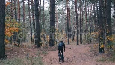 有吸引力的专业自行车骑自行车骑自行车在秋天的森林。 年轻英俊的男运动员在秋天骑自行车
