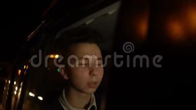 年轻英俊的少年在夜间城市和司机一起乘坐出租车旅行的肖像。 4k个镜头