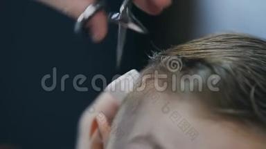 理发师正在理发店剪男孩`头发。 专业理发师在理发店理发. 男孩