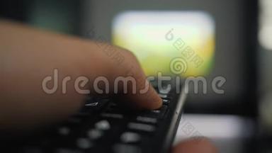 一个手里拿着<strong>遥控</strong>器的人看电视，按下<strong>遥控</strong>器上的按钮。