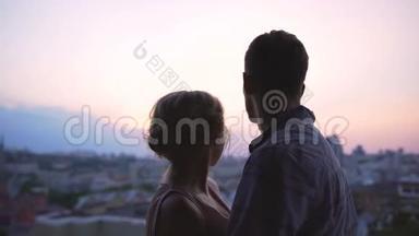 一对欣赏美丽的粉红色日落的夫妇<strong>轻轻地</strong>笼罩着他们，<strong>从</strong>屋顶眺望