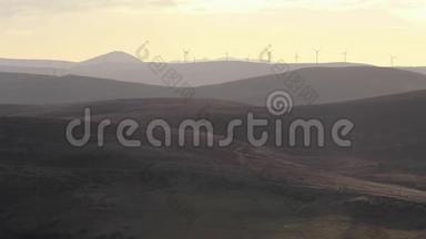 标题：苏格兰凯恩戈姆国家公园附近的群山中，风电场映衬着日出。