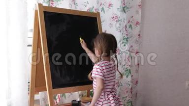 学龄前小女孩<strong>在黑板上写字</strong>母。 幼儿女孩拿着粉笔画画。