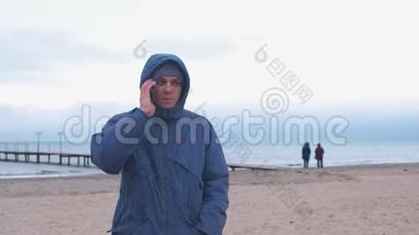 冬天穿着夹克的人在<strong>海边</strong>的<strong>海边</strong>玩手机。