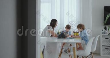 妈妈帮儿子<strong>学画</strong>做作业学前准备在家坐在白色厨房.. 两个孩子
