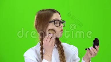 戴眼镜的女学生用刷子擦鼻子，照镜子. 绿色屏幕