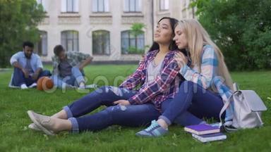 金发女孩支持她最好的朋友，<strong>学生们</strong>坐在校园附近的草坪上。