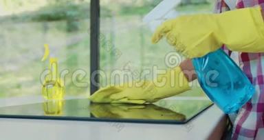 用除脂剂<strong>喷雾</strong>剂和一名戴黄色橡胶手套的妇女的<strong>喷雾</strong>器清洁厨房的烹饪面板。
