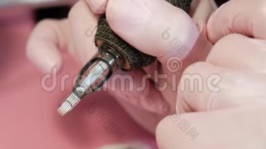 纹身师傅在纹身机上插针.. 红色背景上的粉红色安全手套。