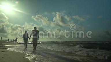 一位年轻的父亲和他的儿子沿着海滨散步。 阳光灿烂. 他们在说话。 家庭幸福。 <strong>信托</strong>基金