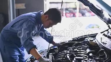 年轻的亚洲<strong>汽车</strong>机械师在<strong>汽车</strong>修理<strong>车</strong>间的<strong>汽车</strong>引擎盖检查发动机。 维修人员检查客户安全