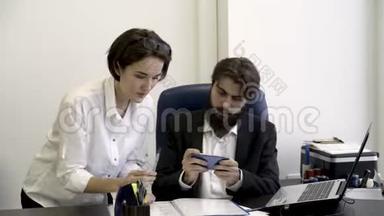 女秘书把重要的文件展示给她那长胡子的老板，她在办公室里忙着玩智能手机游戏