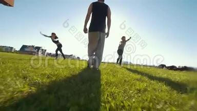 在草地上表演杂技的年轻女子，站在她们中间的年轻人的剪影