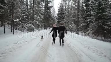 年轻漂亮的家庭在冬天的森林里和一只狗玩。 男人和女人在森林里和比格一起跑步。