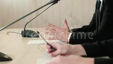 演讲者与一名助理在新闻发布会上，手与文件特写，侧视..