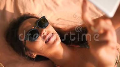 热带海滩上使用移动平板小玩意的年轻微笑混合种族<strong>旅游</strong>妇女肖像。 4K，慢动作。 <strong>普吉岛</strong>