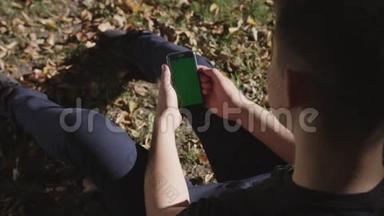 男子手持黑色智能手机，绿色屏幕上的城市街道背景在晴天。 大屏幕。 科布尔街