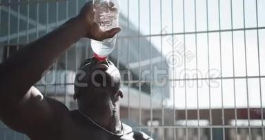 黑人疲惫的非裔美国男<strong>运动</strong>员经过艰苦的训练后喝干净的凉水。 交叉配合训练。 工作安排