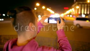 在夜城用相机<strong>拍照</strong>的人。 年轻的休闲男子在外面用相机手机<strong>拍照</strong>。