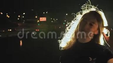 女孩肖像剪影，头发在微风中挥动在夜间城市背景。 城市灯光中的轻发.. 火灾