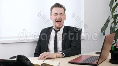 穿西装的年轻商人坐在办公室里，伸着舌头，使滑稽的脸60英尺长