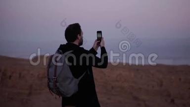人类拍摄智能手机照片惊人的紫罗兰天空。 慢动作。 紫罗兰色的黄昏，沙漠的山色，大气的景色