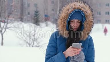 冬天降雪时，年轻漂亮的女人在户外打电话。