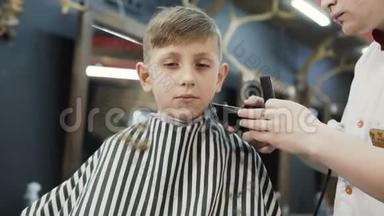 男孩7-8岁在理发店。 <strong>美容</strong>院快乐的小男孩。 男巫做发型孩子。 巴伯切断了