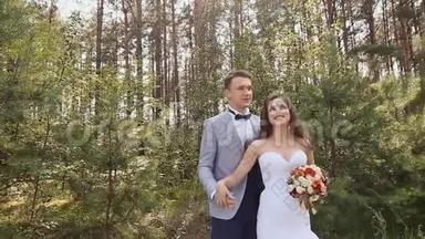 新娘和新郎在森林里摆姿势。 新郎亲吻拥抱新娘。 一对恩爱夫妻的幸福时刻