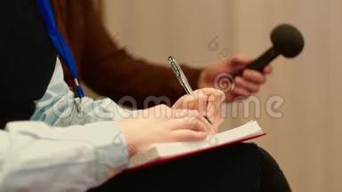 记者在新闻发布会上做笔记的笔记本和录音，双手特写，侧视..