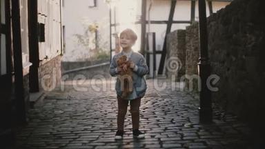 可爱的白人男孩在外面唱<strong>歌</strong>的肖像。 男孩子看着古老铺成的镇街上的摄像机。 太阳耀斑4K。