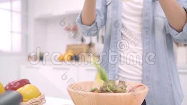 慢动作-年轻的亚洲女人在厨房里做沙拉健康<strong>食品</strong>，漂亮的女人在随意使用有机<strong>食品</strong>。