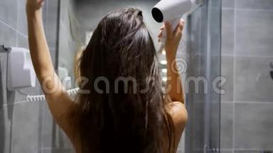 手拿电吹风，在酒店客房浴室吹湿头发