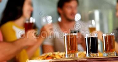 三杯威士忌放在桌上，朋友在4k背景下喝一杯啤酒