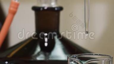 液体滴出的水滴从吸管尖落到杯中，用黑色的瓶子