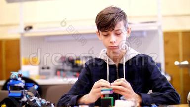 这个12岁的男孩，从立方体、盘子、电路、电线中扮演设计师。 小发明家创造机器人