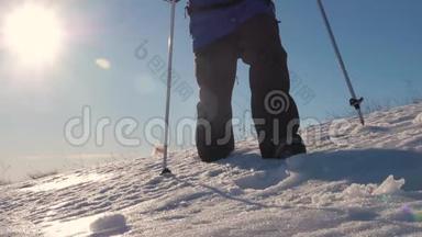 徒步旅行者在冬天寒冷的雪天徒步旅行。 在山脉的背景下，腿沿着山脊走