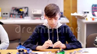 这个12岁的男孩，从立方体、盘子、电路、电线中扮演设计师。 小发明家创造机器人