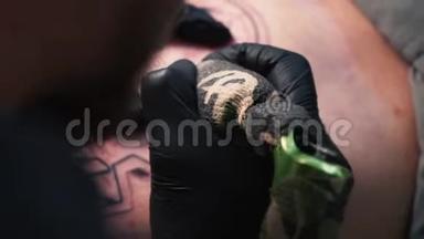 乌克兰，基辅，2018年5月20日。 为顾客做纹身的艺术家的手，戴着黑色手套的纹身艺术家做纹身