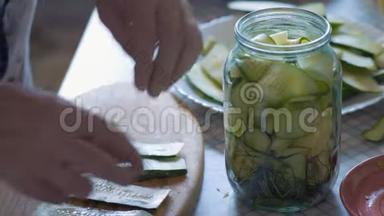 特写镜头，一位老年妇女的手将一片片白胡椒<strong>放入</strong>黄瓜片中，并将其<strong>放入</strong>玻璃罐中