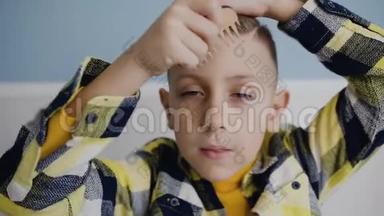 孩子正在用<strong>木梳</strong>梳理头发，看着镜头.. 一个蓝眼睛男孩的肖像